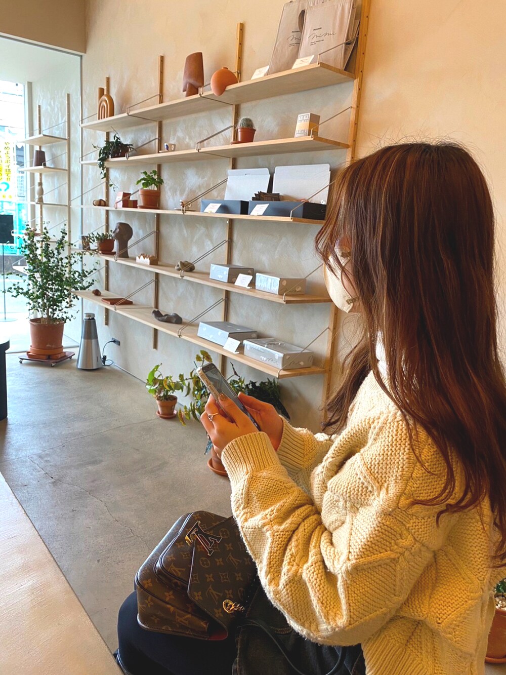 ホワイト系のニット/セーター、ブラウン系のバッグ、ブルー系のデニムスカートを着用したレディースの冬コーディネートの3枚目の写真