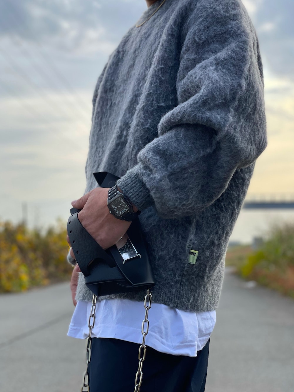 ブルー系のダウンジャケット/コート、グレー系のニット/セーター、ブラック系のその他パンツを着用したメンズの秋コーディネートの4枚目の写真