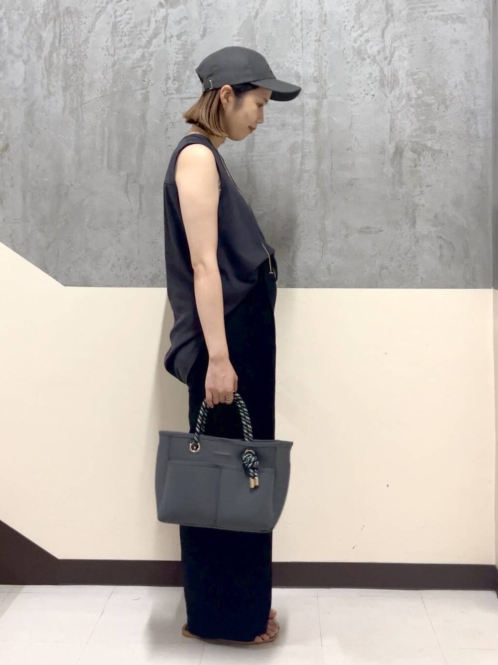 グレー系のトートバッグ、グレー系のTシャツ/カットソー、ブラック系のスラックスを着用したレディースの夏コーディネートの4枚目の写真