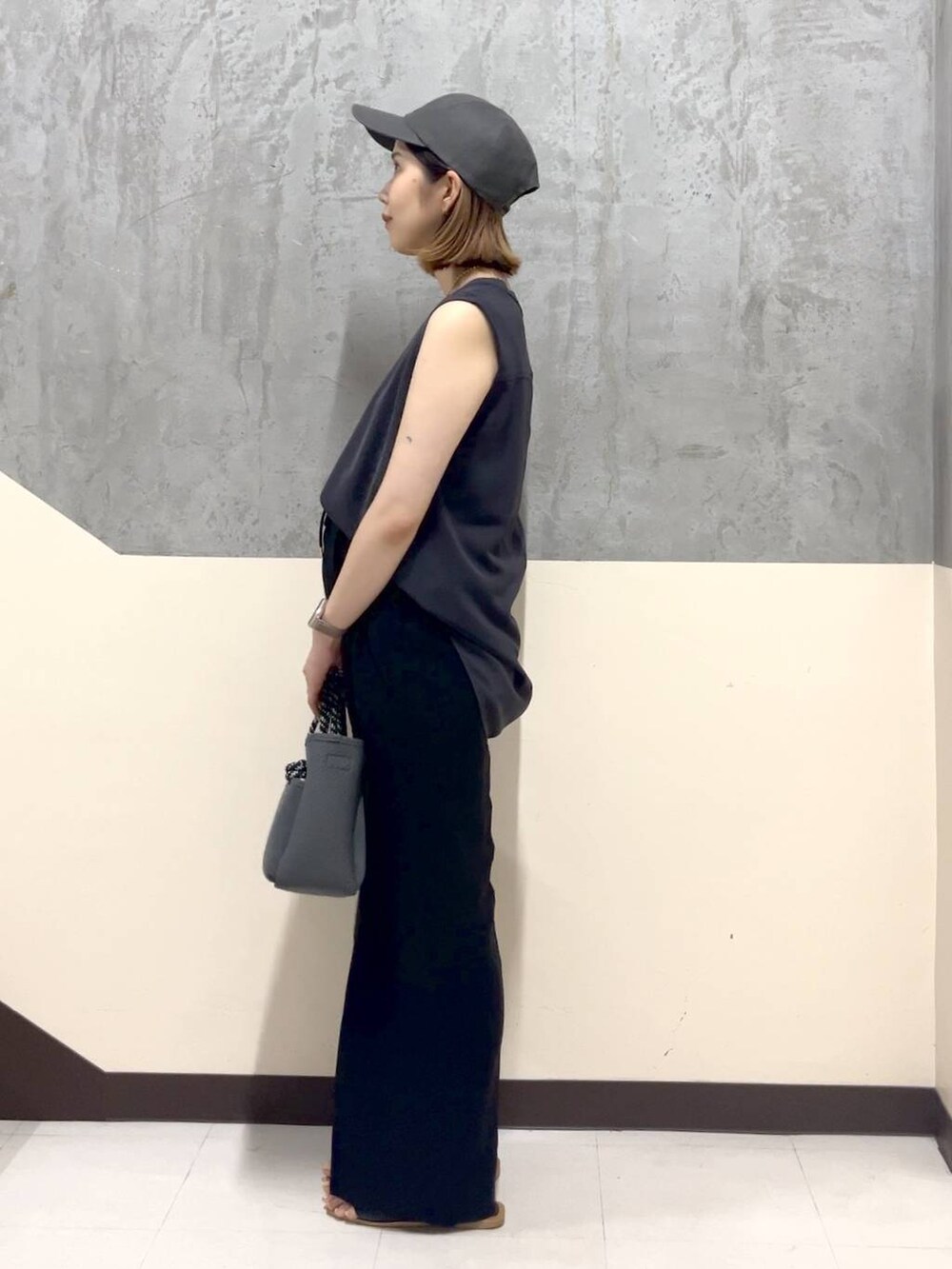 グレー系のトートバッグ、グレー系のTシャツ/カットソー、ブラック系のスラックスを着用したレディースの夏コーディネートの2枚目の写真