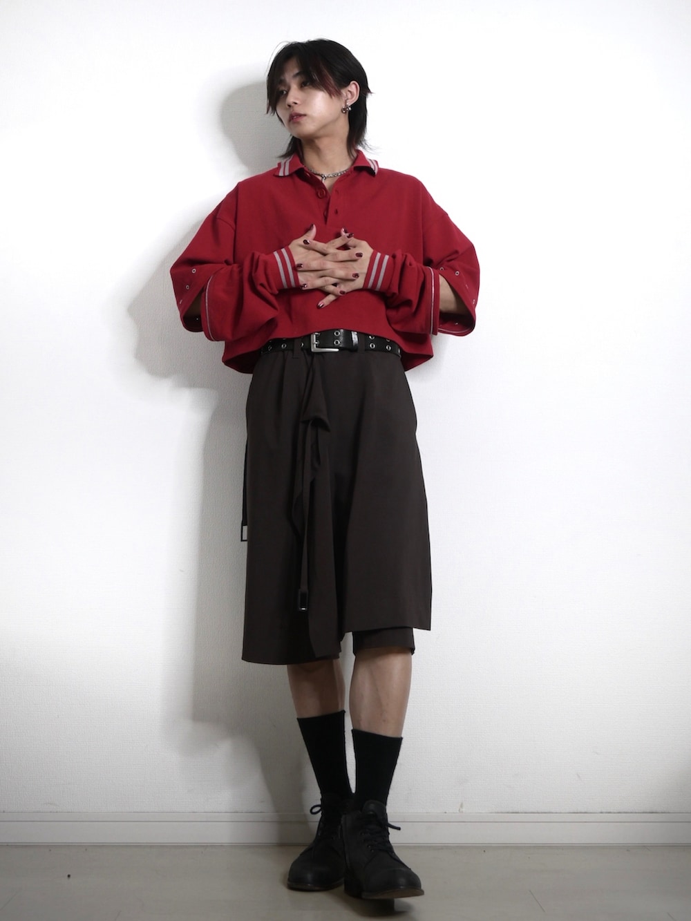 レッド系のポロシャツ、ブラウン系のパンツ、ブラック系のシューズを着用したメンズの夏コーディネートの3枚目の写真