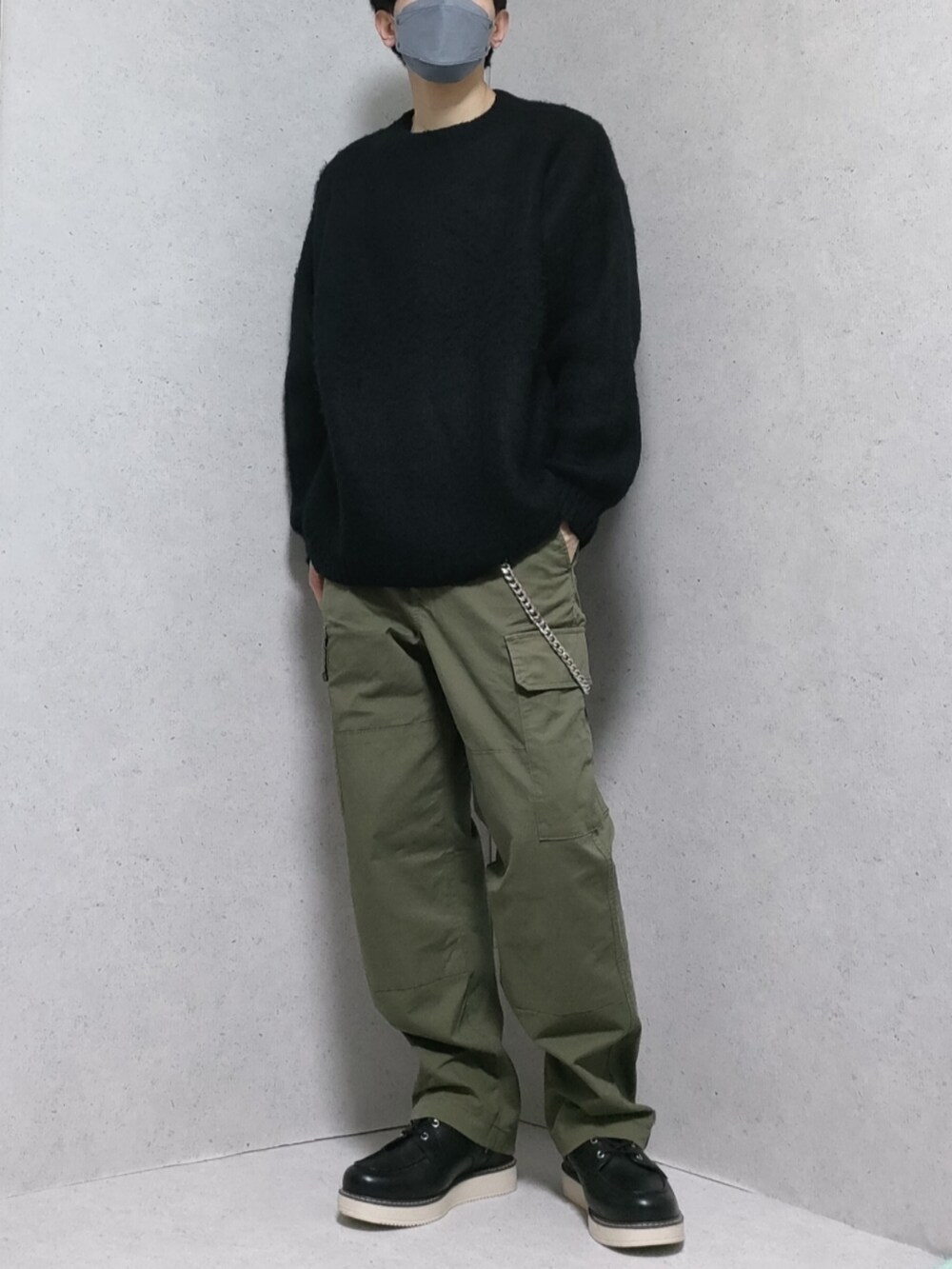 グリーン系のカーゴパンツ、ブラック系のブーツ、グレー系のニット/セーターを着用したメンズの秋コーディネートの2枚目の写真