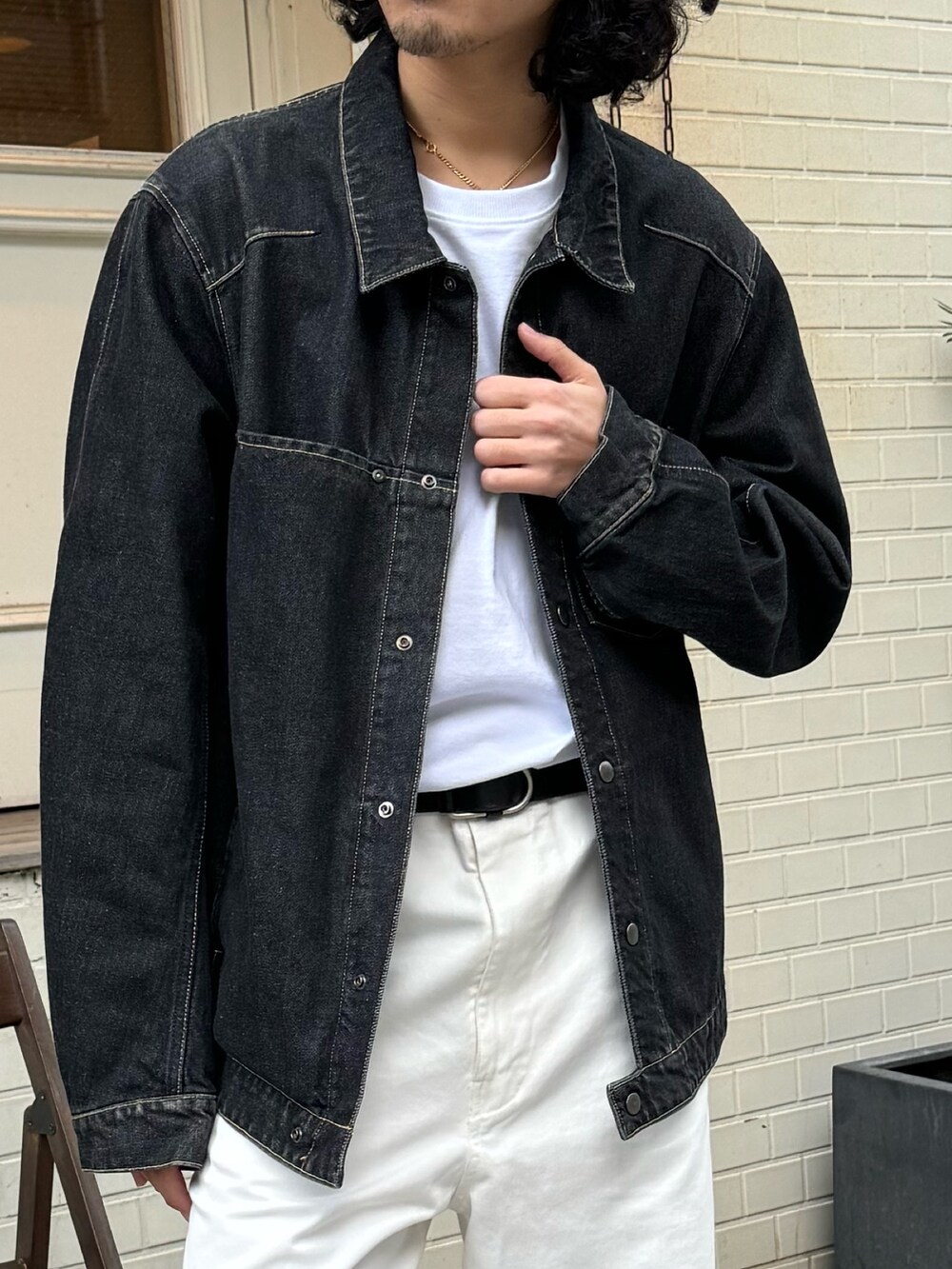 ブラック系のデニムジャケット、ホワイト系のチノパンツ、レッド系のキャップを着用したメンズの冬コーディネートの2枚目の写真