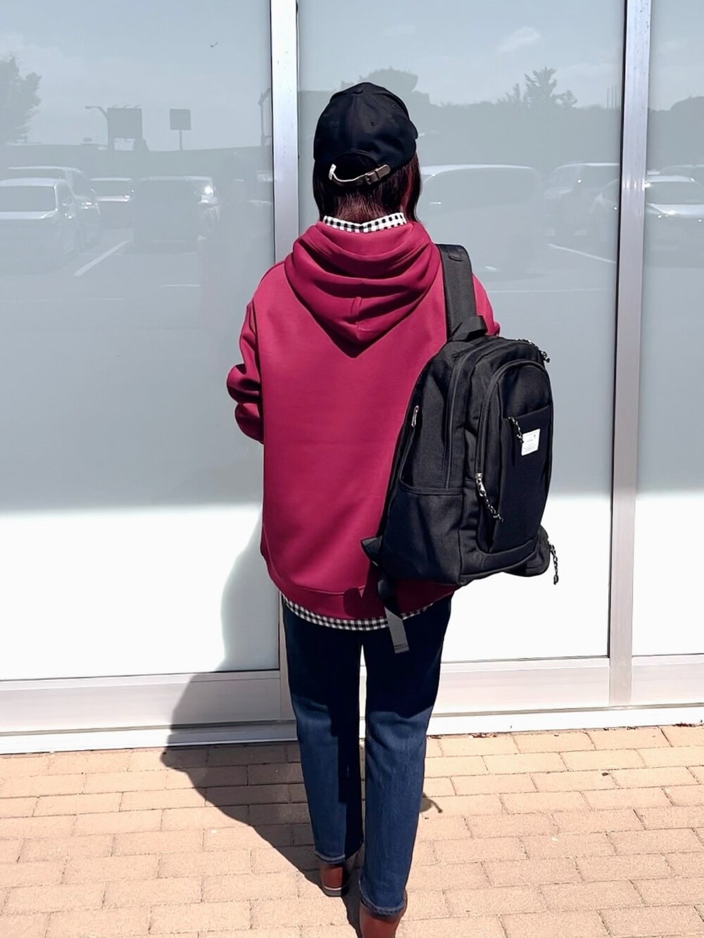 レッド系のパーカー、ブラック系のシャツ/ブラウス、ブルー系のデニムパンツを着用したレディースの秋コーディネートの2枚目の写真