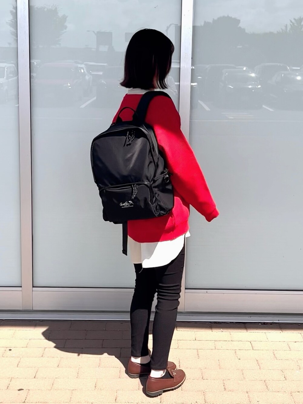 レッド系のニット/セーター、ブラック系のその他パンツ、ブラック系のバックパック/リュックを着用したレディースの秋コーディネートの2枚目の写真