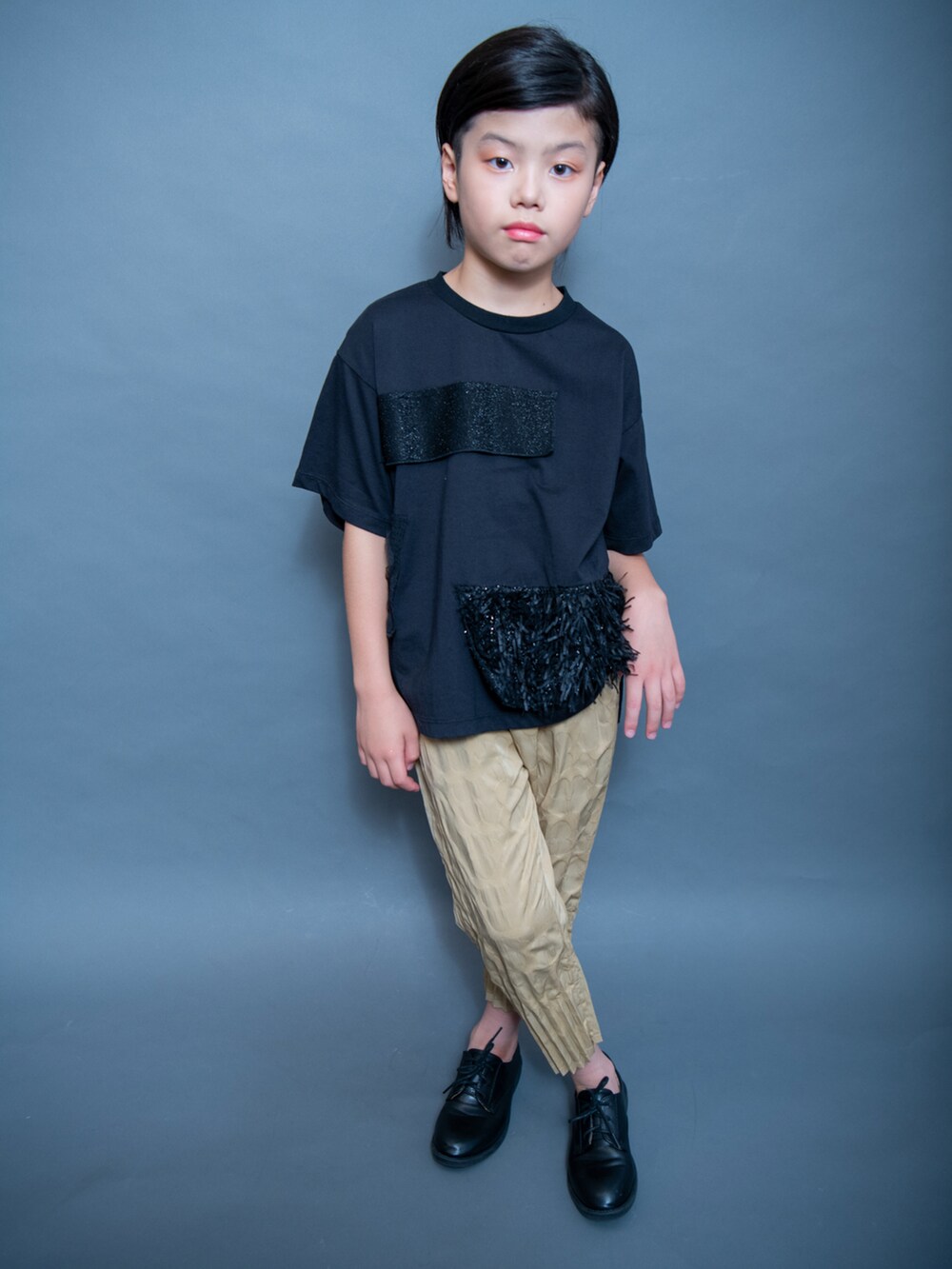 ブラック系のTシャツ/カットソー、ゴールド系のパンツ、ブラック系のシューズを着用したキッズの夏コーディネートの2枚目の写真