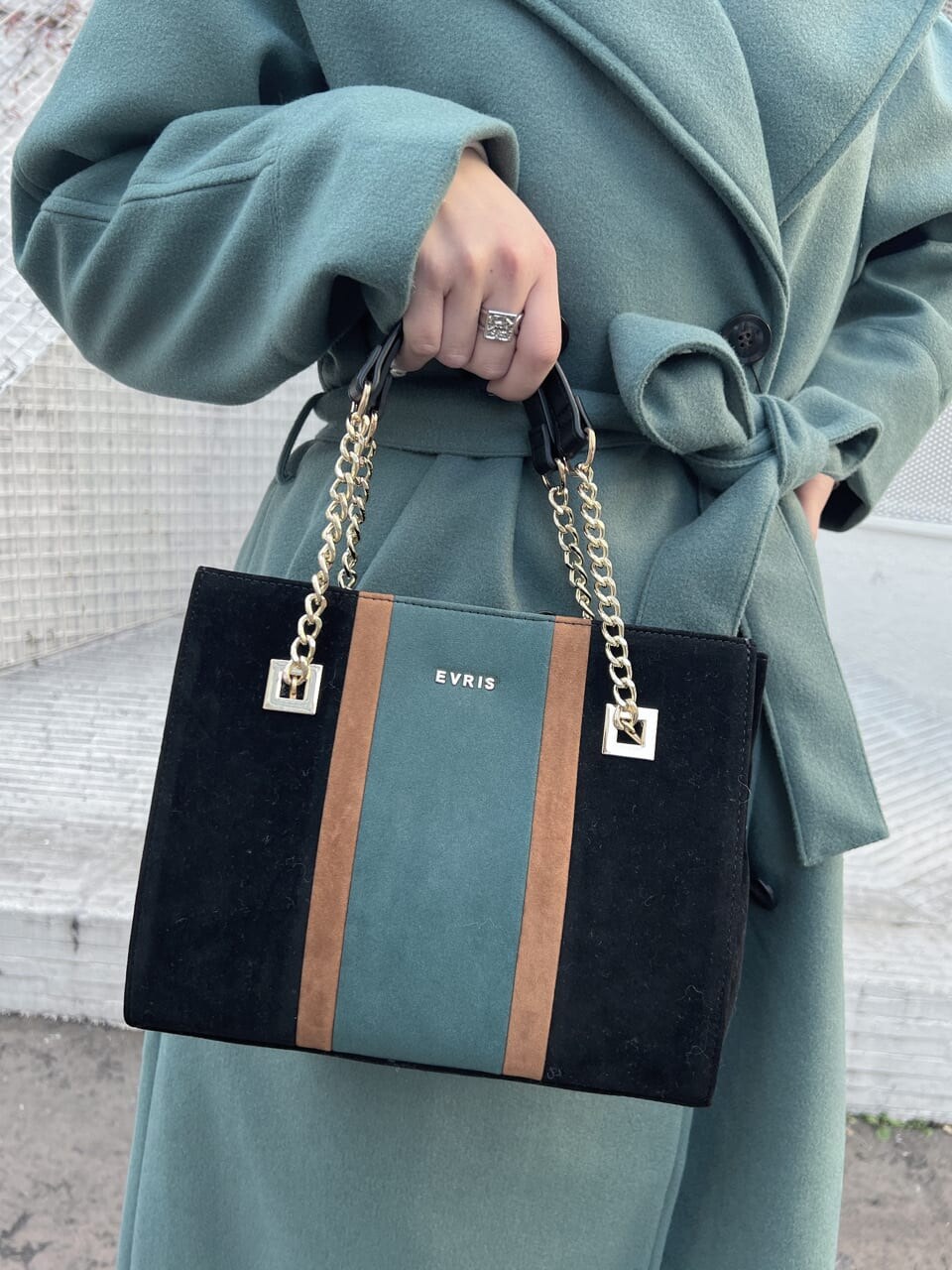 ブラック系のショルダーバッグ、グリーン系のチェスターコート、ホワイト系のTシャツ/カットソーを着用したレディースの冬コーディネートの7枚目の写真