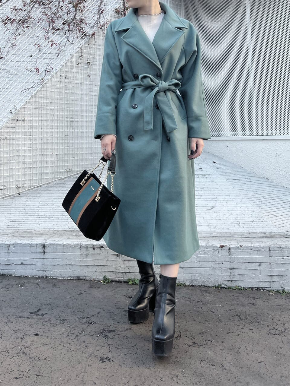 ブラック系のショルダーバッグ、グリーン系のチェスターコート、ホワイト系のTシャツ/カットソーを着用したレディースの冬コーディネートの3枚目の写真