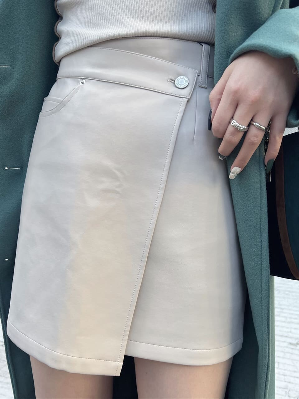 ブラック系のショルダーバッグ、グリーン系のチェスターコート、ホワイト系のTシャツ/カットソーを着用したレディースの冬コーディネートの5枚目の写真