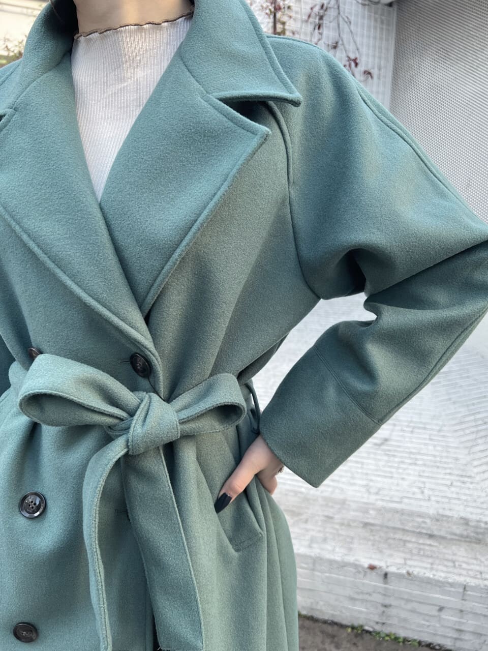 ブラック系のショルダーバッグ、グリーン系のチェスターコート、ホワイト系のTシャツ/カットソーを着用したレディースの冬コーディネートの6枚目の写真