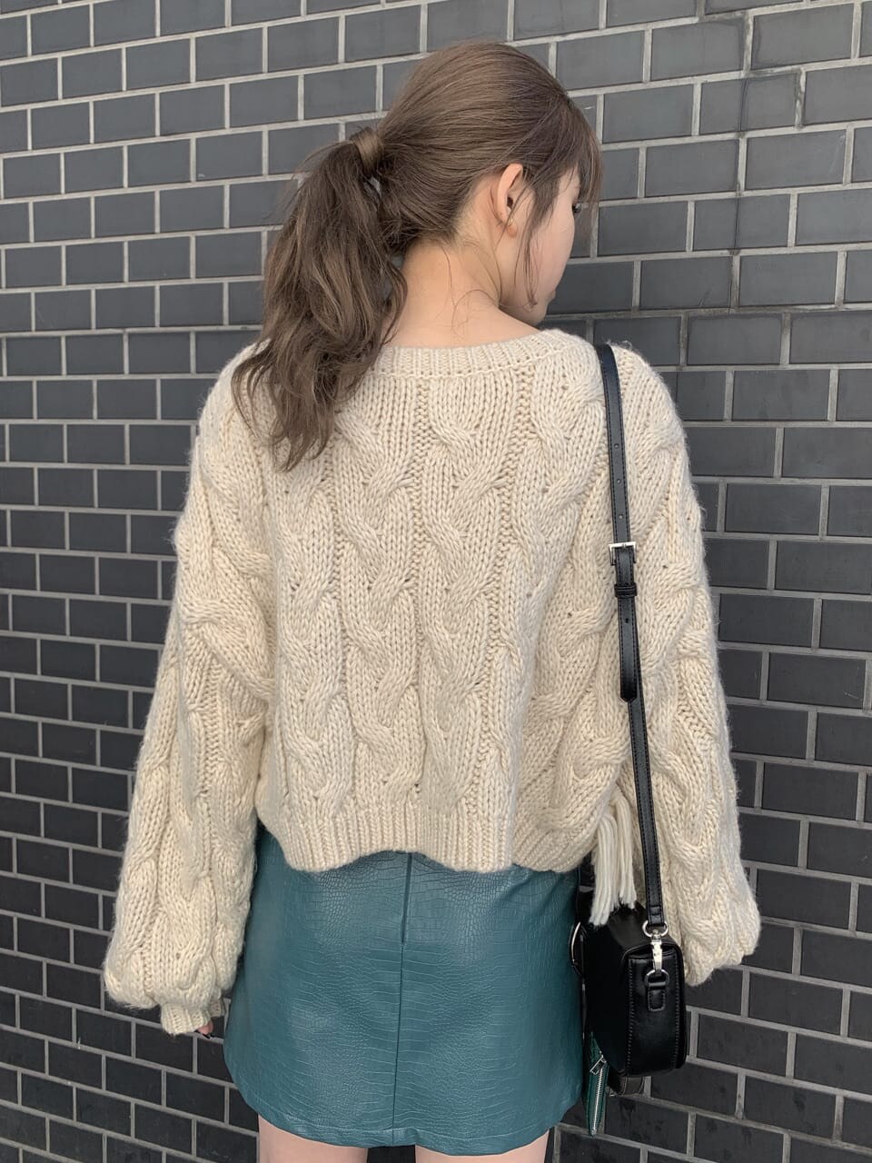 ブラック系のブーツ、ブラック系のショルダーバッグ、ホワイト系のニット/セーターを着用したレディースの秋コーディネートの2枚目の写真