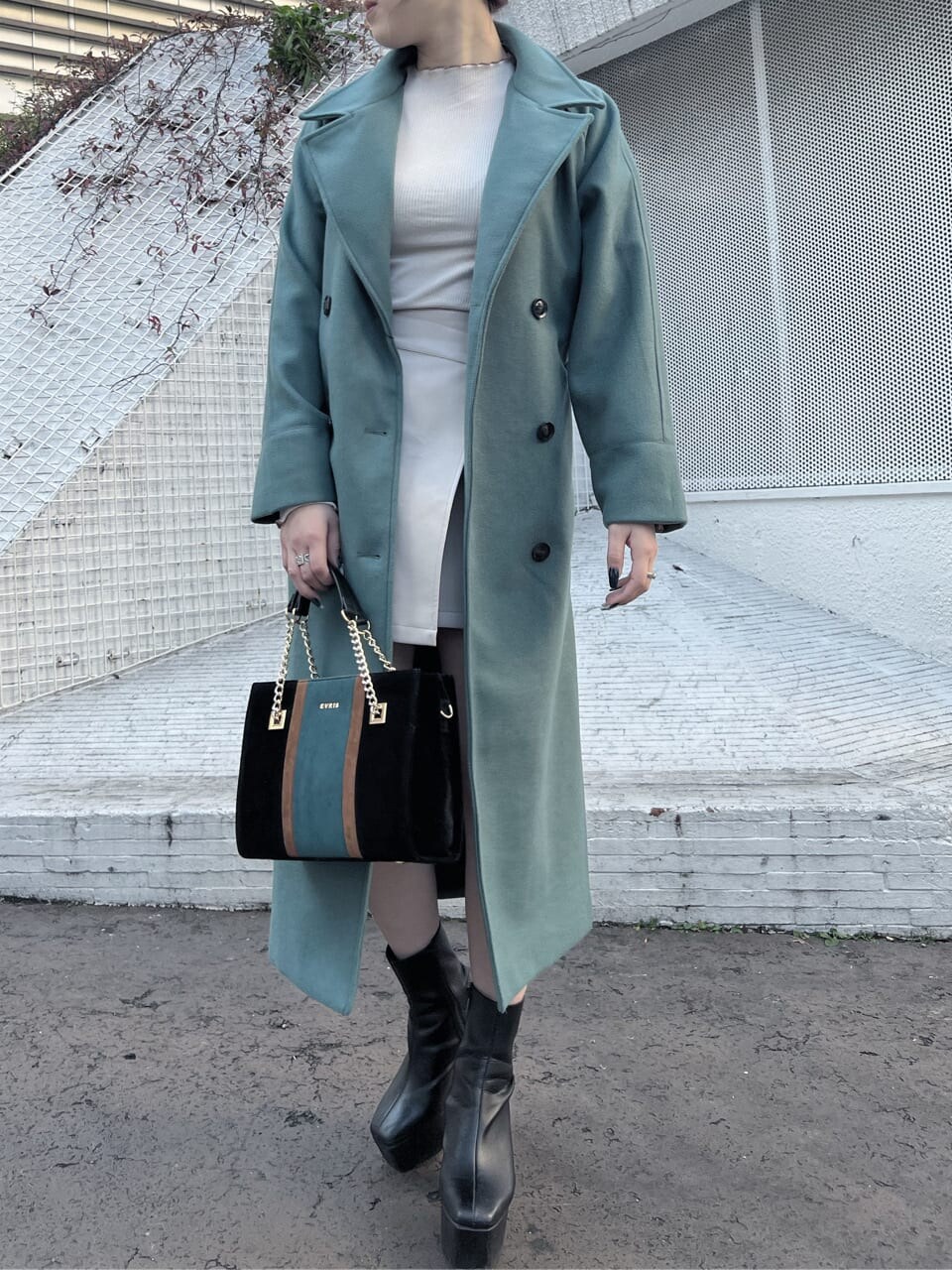 ブラック系のショルダーバッグ、グリーン系のチェスターコート、ホワイト系のTシャツ/カットソーを着用したレディースの冬コーディネートの4枚目の写真