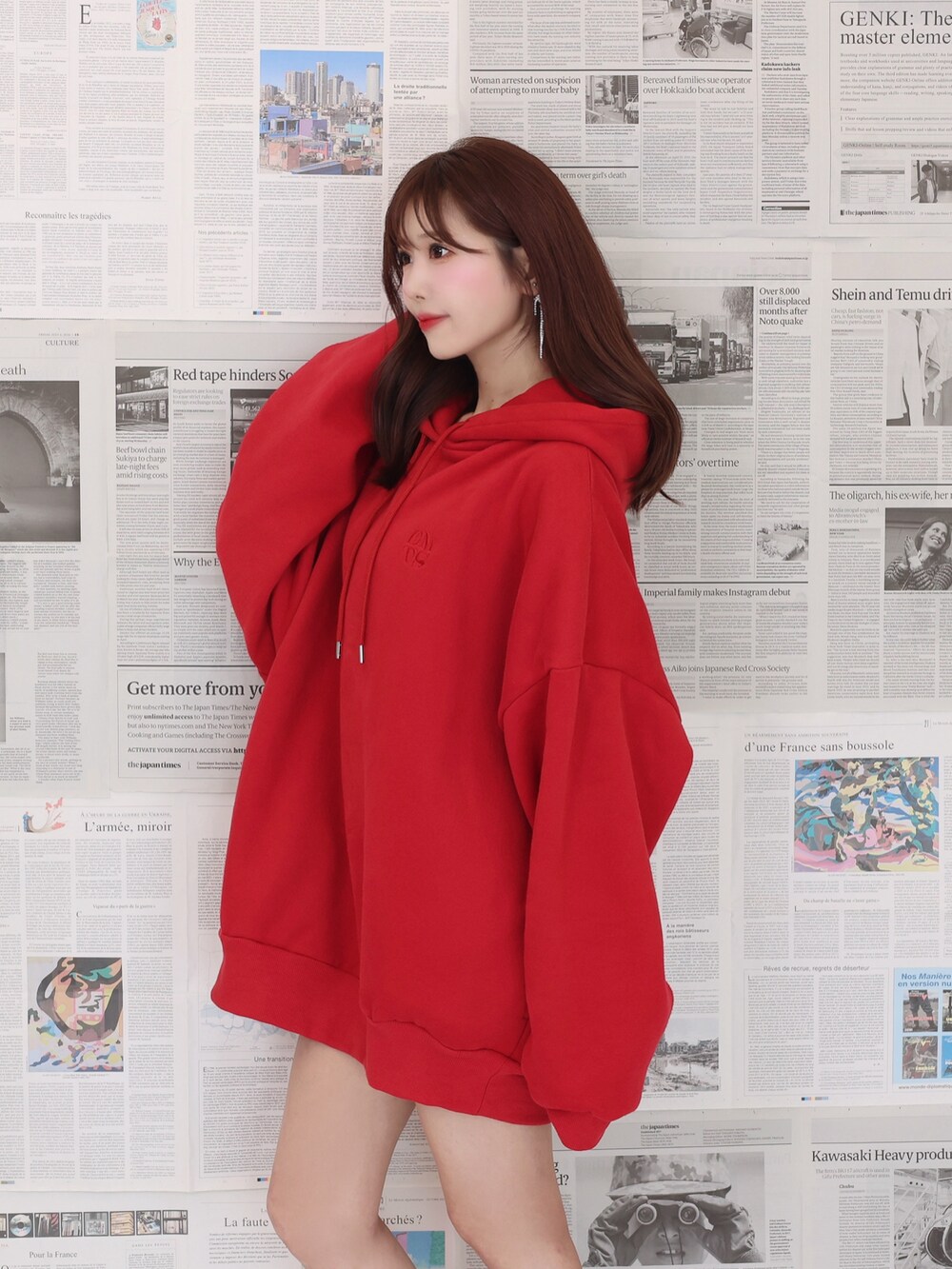 レッド系のパーカー、ブラック系のショルダーバッグ、ブラック系のブーツを着用したレディースの夏コーディネートの3枚目の写真