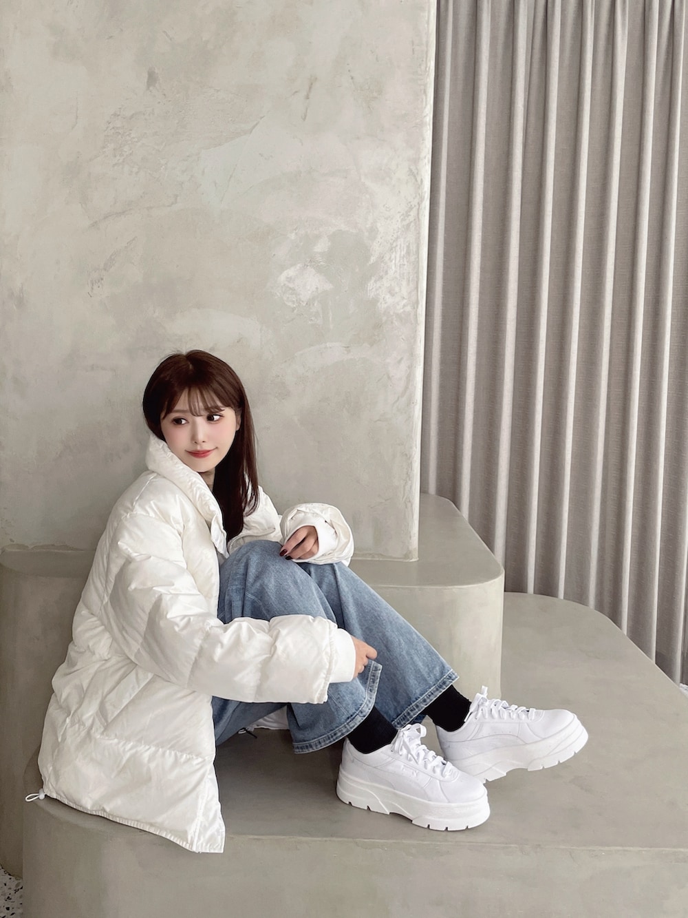 ホワイト系のダウンジャケット/コート、ブルー系のデニムパンツ、ホワイト系のスニーカーを着用したレディースの秋コーディネートの3枚目の写真