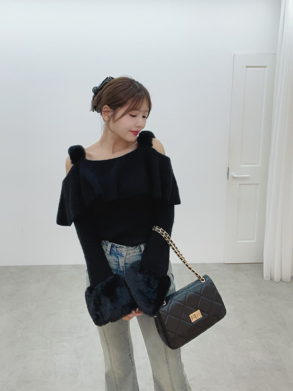 ブラック系のハンドバッグ、ブルー系のデニムパンツ、ブラック系のニット/セーターを着用したレディースの秋コーディネートの9枚目の写真