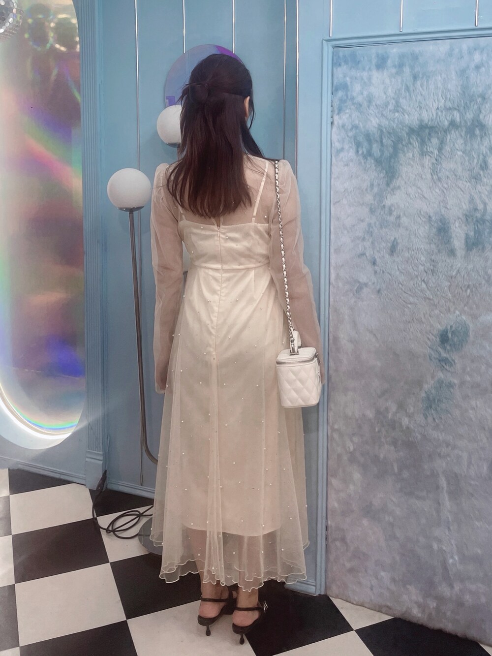 ホワイト系のワンピース、ブラック系のパンプス、ホワイト系のハンドバッグを着用したレディースの秋コーディネートの7枚目の写真