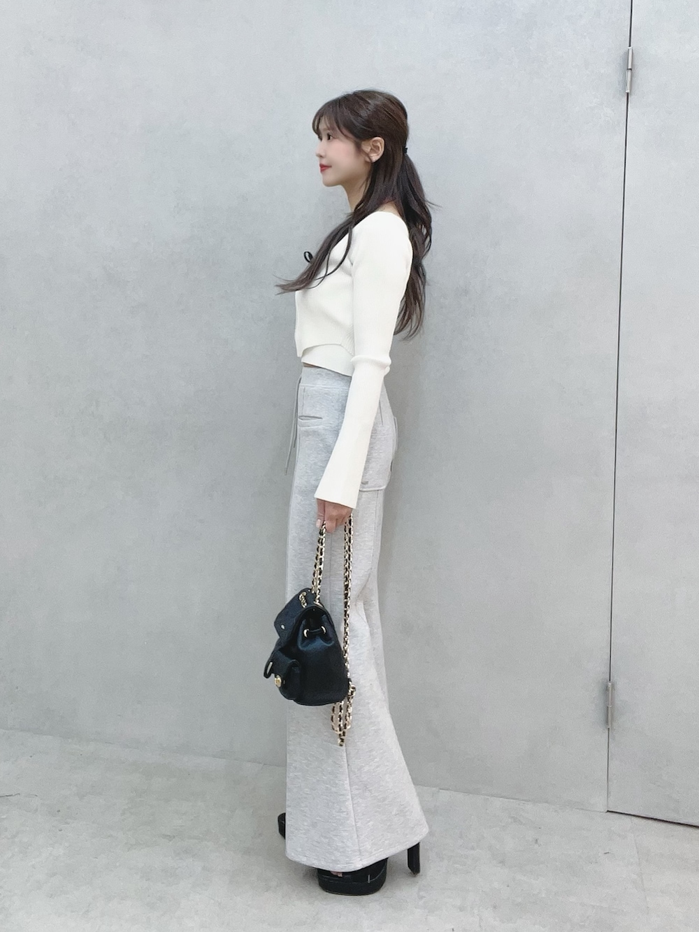 ホワイト系のニット/セーター、グレー系のその他パンツ、ブラック系のバックパック/リュックを着用したレディースの冬コーディネートの4枚目の写真