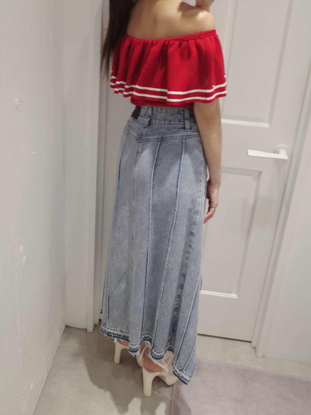 レッド系のニット/セーター、ホワイト系のトートバッグ、ブルー系のデニムスカートを着用したレディースの夏コーディネートの6枚目の写真