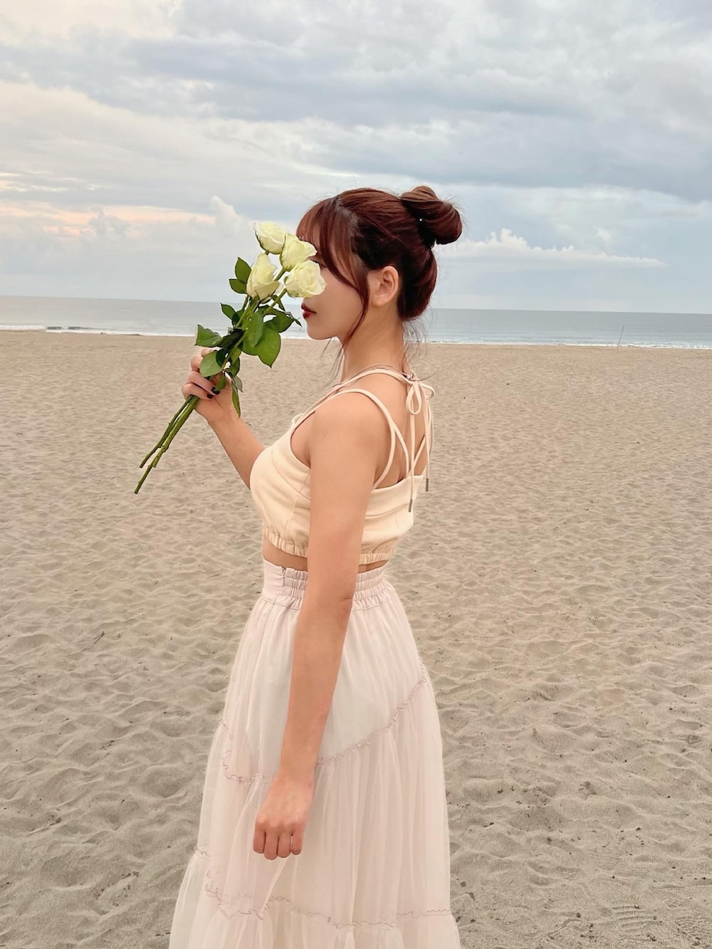 イエロー系のキャミソール、ベージュ系のスカートを着用したレディースの春コーディネートの5枚目の写真