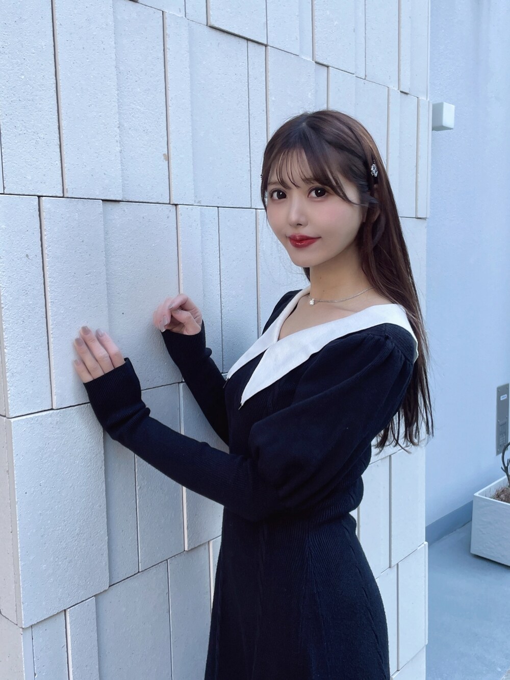 ブラック系のワンピース、レッド系のパンプス、シルバー系のネックレスを着用したレディースの冬コーディネートの2枚目の写真