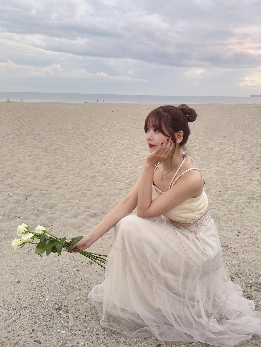 イエロー系のキャミソール、ベージュ系のスカートを着用したレディースの春コーディネートの2枚目の写真