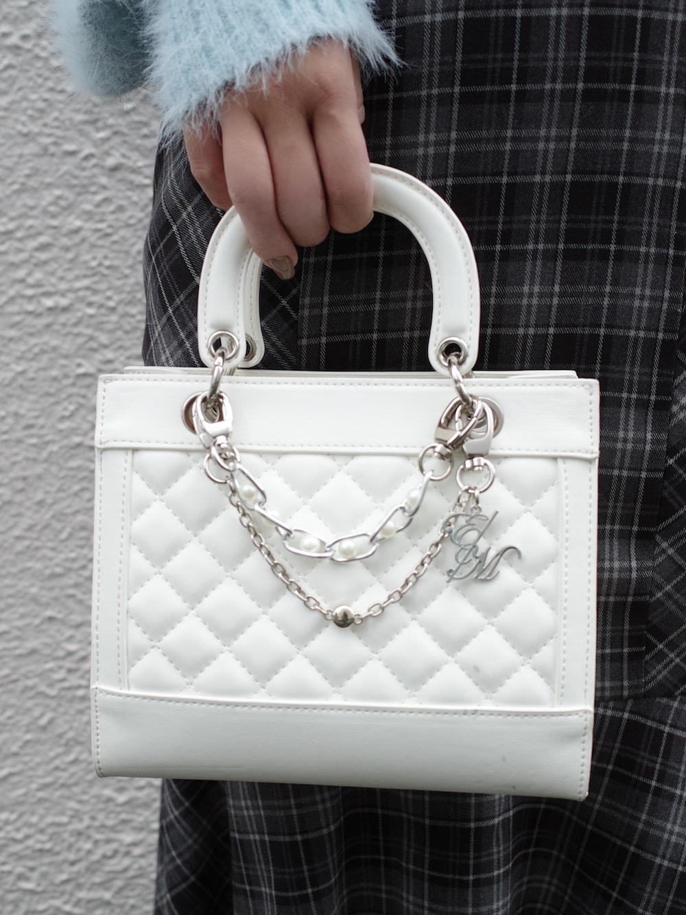 ブルー系のニット/セーター、ホワイト系のハンドバッグ、ブラック系のワンピースを着用したレディースの秋コーディネートの7枚目の写真