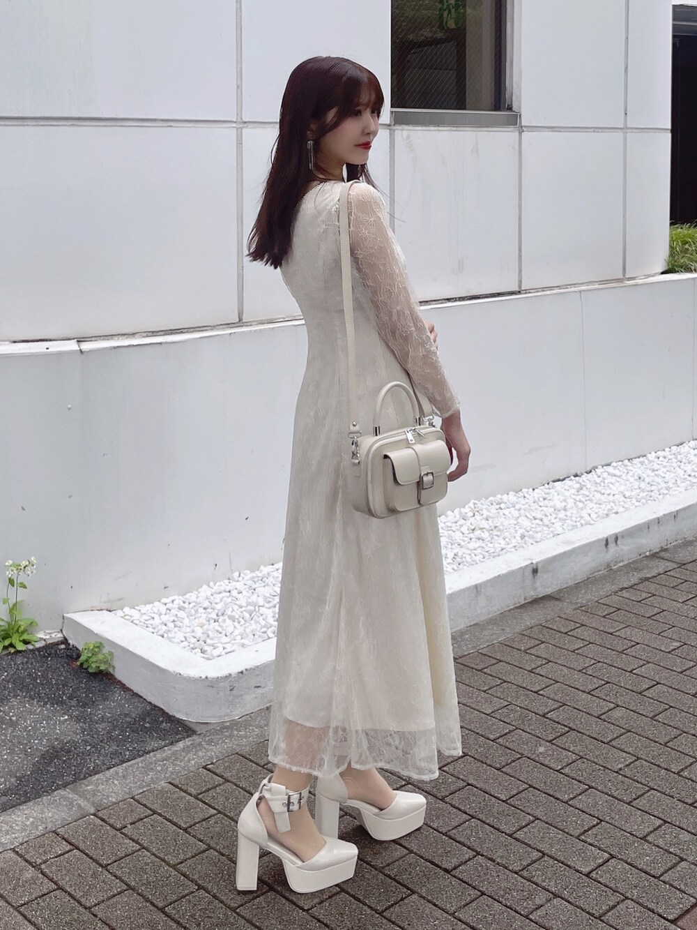ホワイト系のパンプス、ホワイト系のハンドバッグ、ホワイト系のワンピースを着用したレディースの夏コーディネートの2枚目の写真
