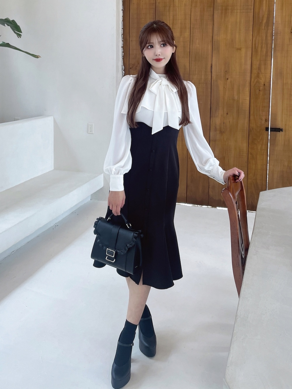 ブラック系のワンピース、ブラック系のショルダーバッグ、ブラック系のパンプスを着用したレディースの冬コーディネートの2枚目の写真