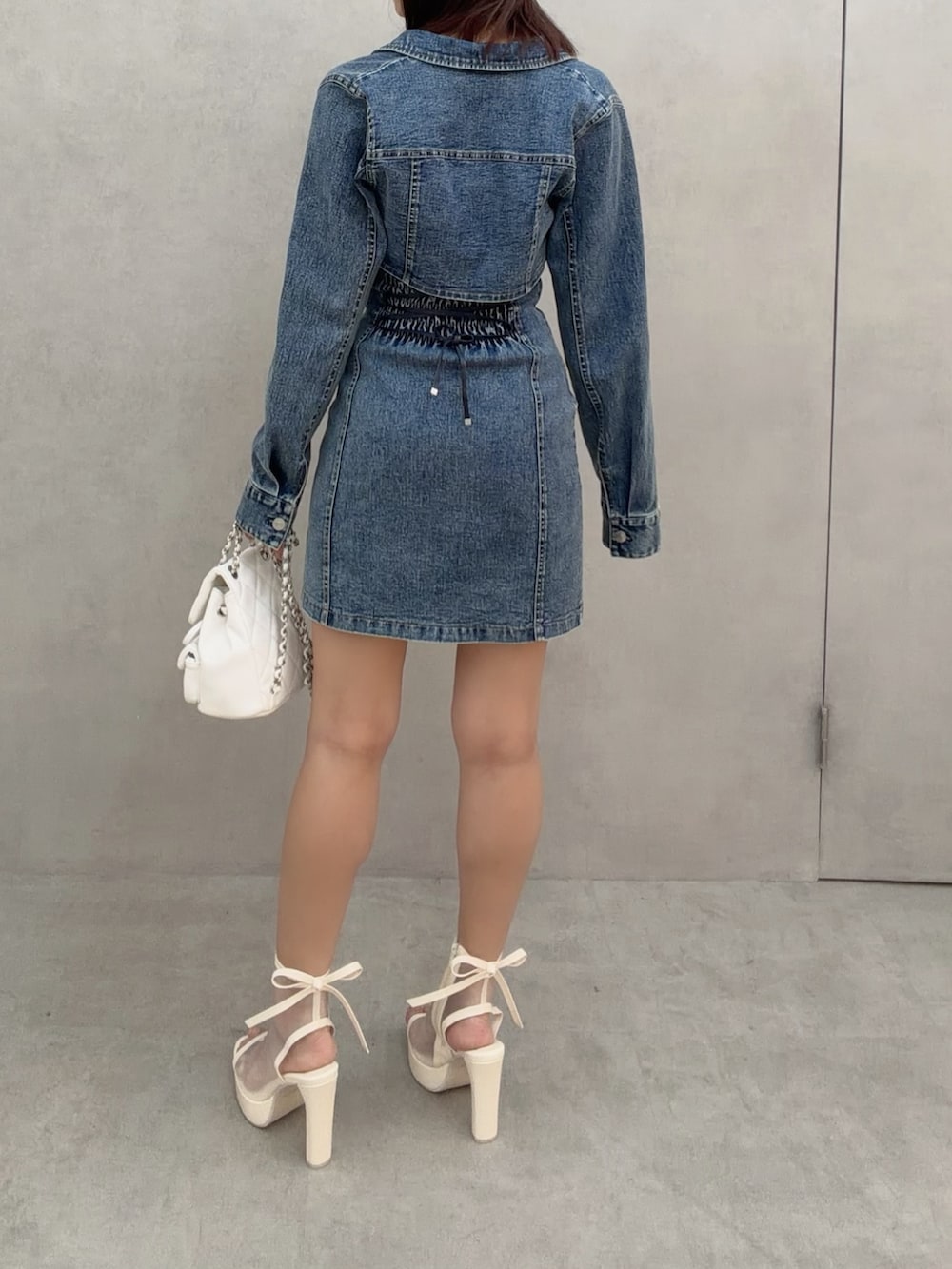 ブルー系のワンピース、ホワイト系のバックパック/リュック、ホワイト系のサンダルを着用したレディースの冬コーディネートの5枚目の写真