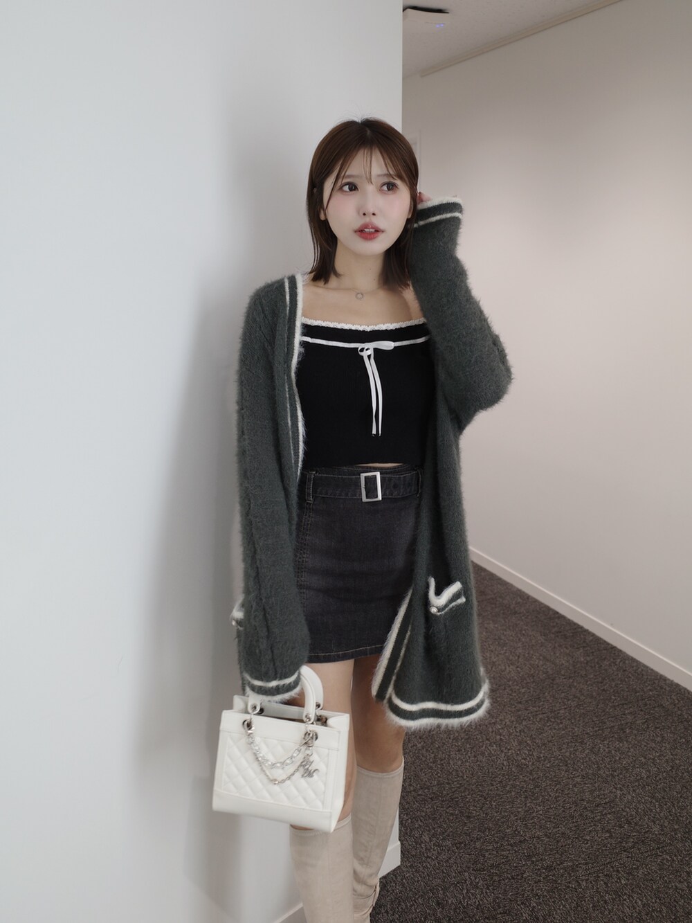 ブラック系のニット/セーター、グレー系のワンピース、ブルー系のデニムスカートを着用したレディースの秋コーディネートの3枚目の写真
