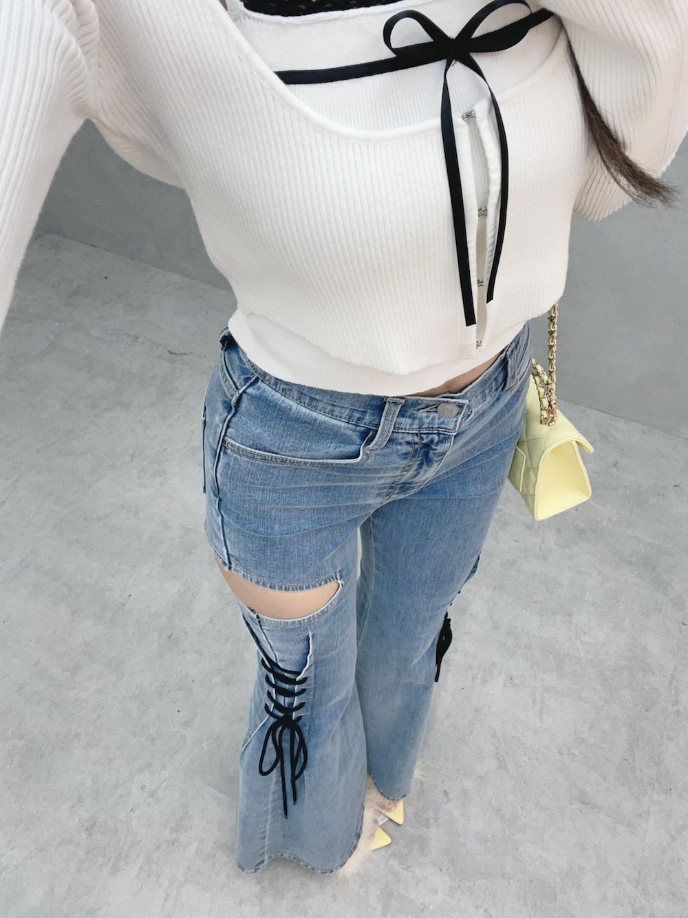 ホワイト系のニット/セーター、イエロー系のサンダル、ブルー系のデニムパンツを着用したレディースの冬コーディネートの7枚目の写真