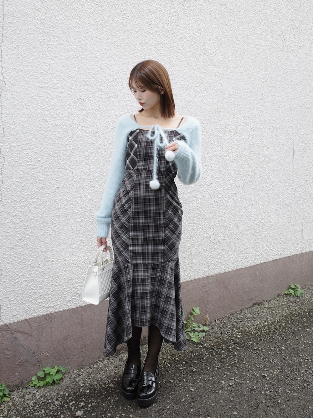 ブルー系のニット/セーター、ホワイト系のハンドバッグ、ブラック系のワンピースを着用したレディースの秋コーディネートの2枚目の写真
