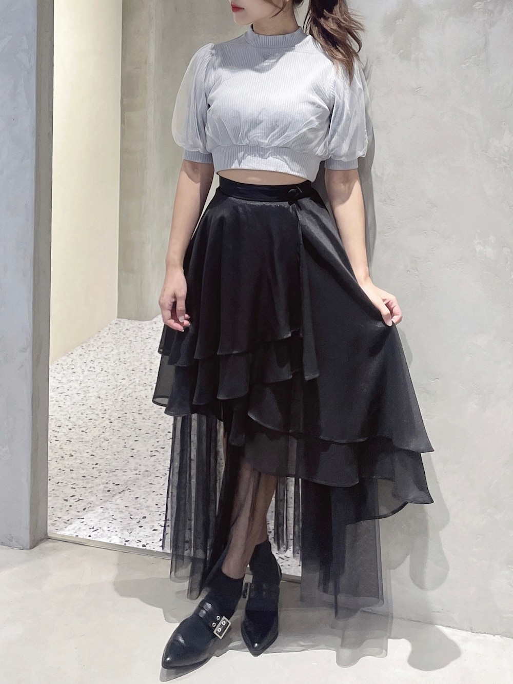 グレー系のニット/セーター、ブラック系のスカート、ブラック系のパンプスを着用したレディースの春コーディネートの2枚目の写真