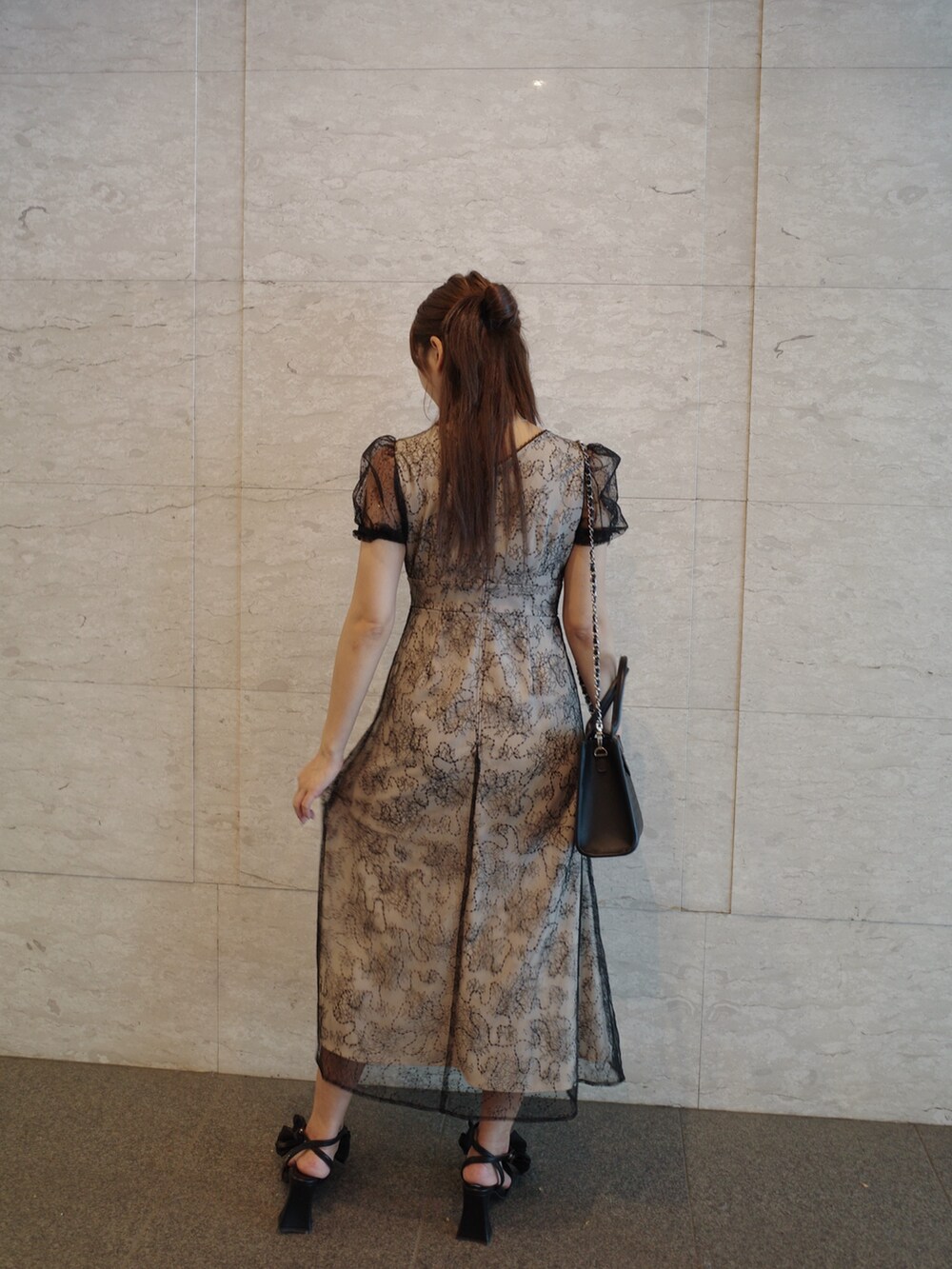 ブラック系のハンドバッグ、ブラック系のパンプス、その他のワンピースを着用したレディースの夏コーディネートの6枚目の写真