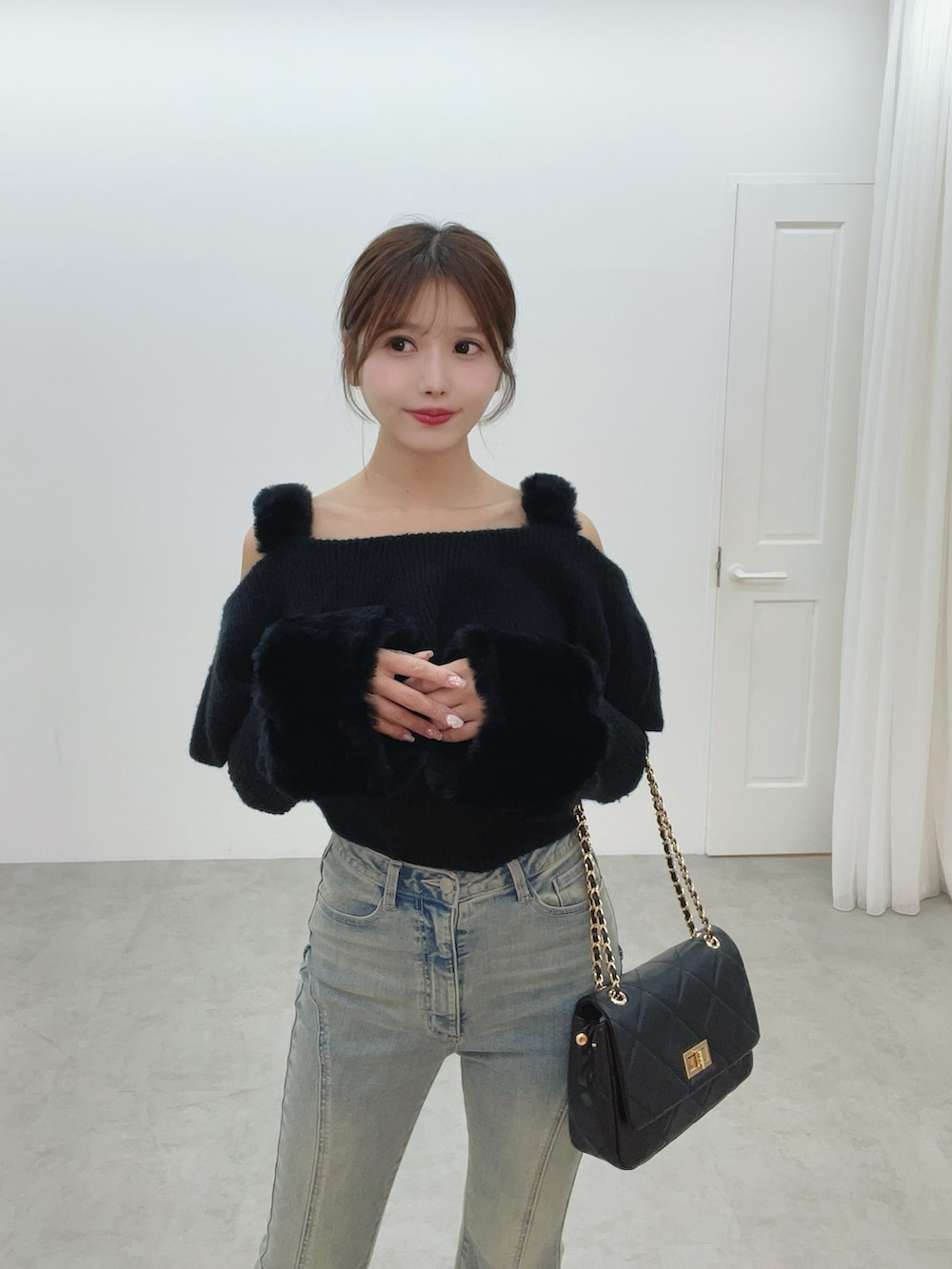 ブラック系のハンドバッグ、ブルー系のデニムパンツ、ブラック系のニット/セーターを着用したレディースの秋コーディネートの7枚目の写真