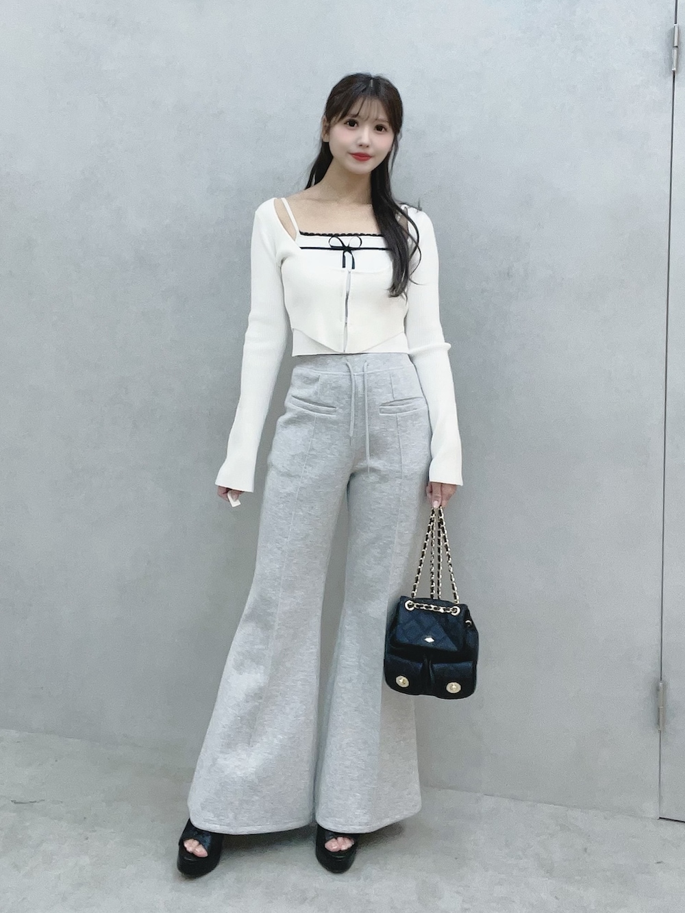 ホワイト系のニット/セーター、グレー系のその他パンツ、ブラック系のバックパック/リュックを着用したレディースの冬コーディネートの3枚目の写真