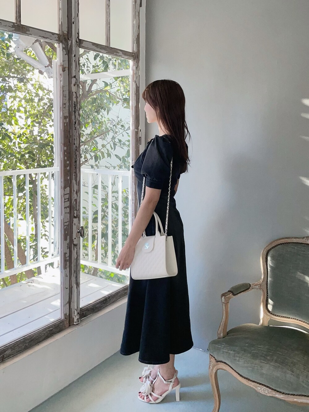 ホワイト系のハンドバッグ、ブラック系のワンピース、ホワイト系のサンダルを着用したレディースの春コーディネートの6枚目の写真