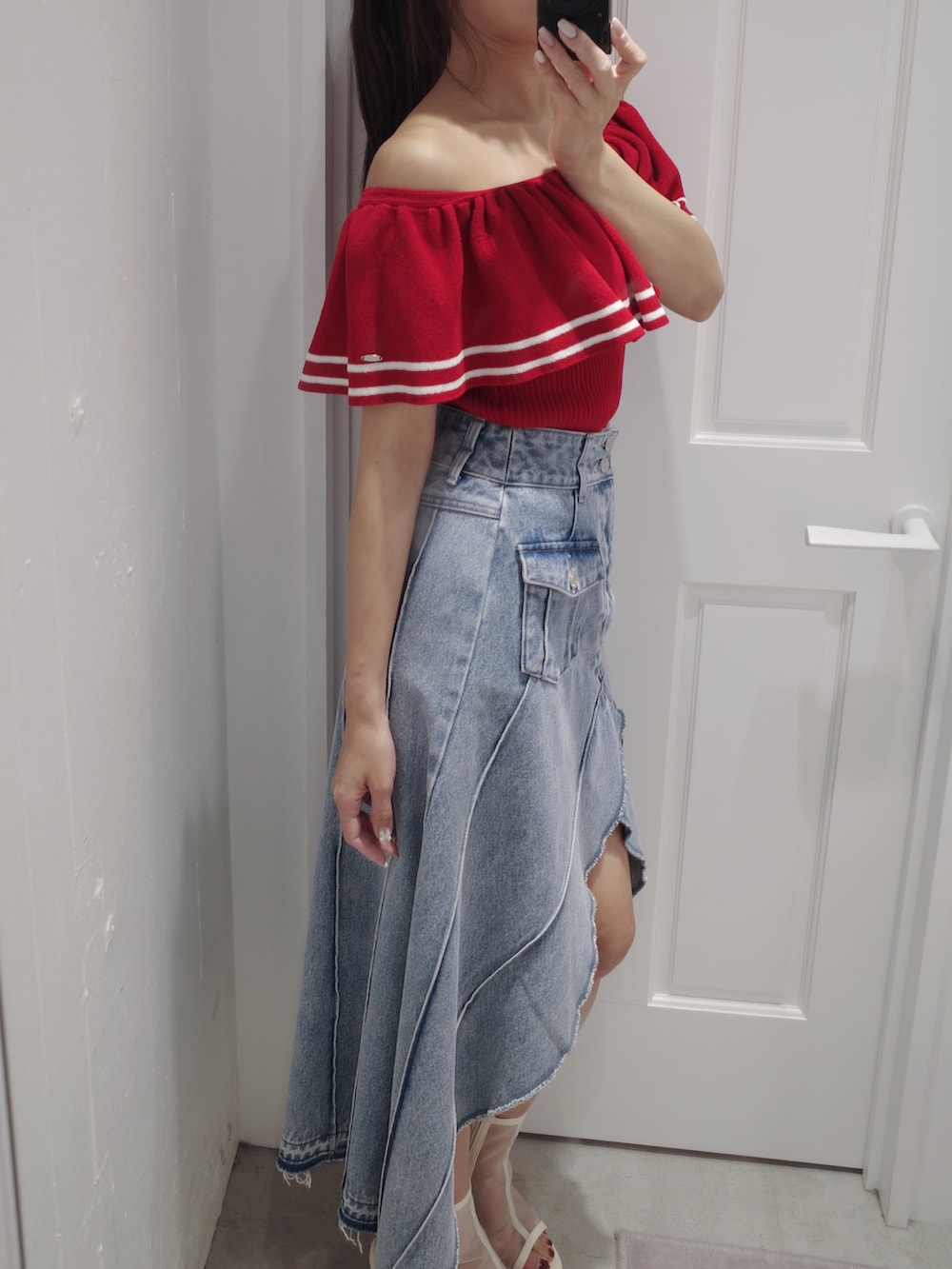 レッド系のニット/セーター、ホワイト系のトートバッグ、ブルー系のデニムスカートを着用したレディースの夏コーディネートの5枚目の写真