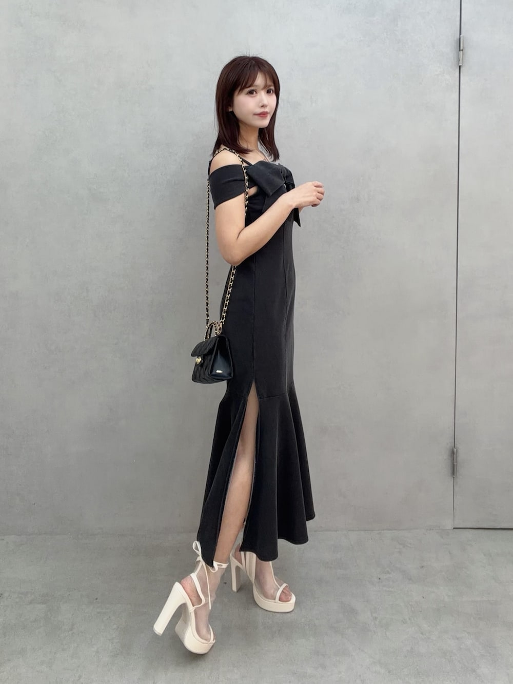 ホワイト系のサンダル、ブラック系のワンピース、ブラック系のハンドバッグを着用したレディースの冬コーディネートの3枚目の写真