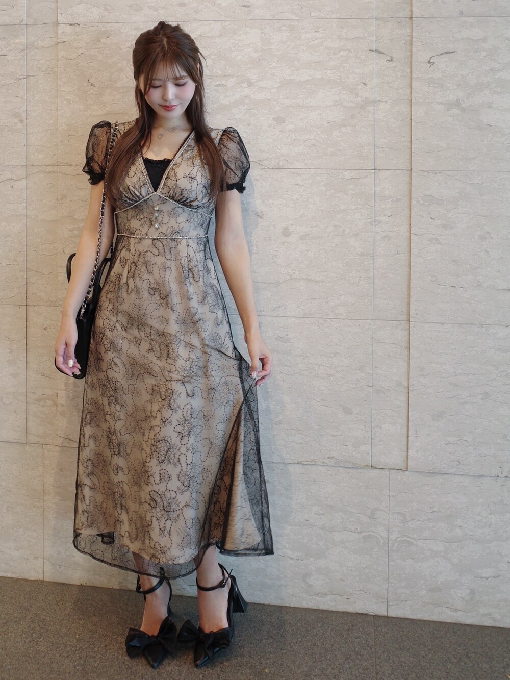 ブラック系のハンドバッグ、ブラック系のパンプス、その他のワンピースを着用したレディースの夏コーディネートの2枚目の写真