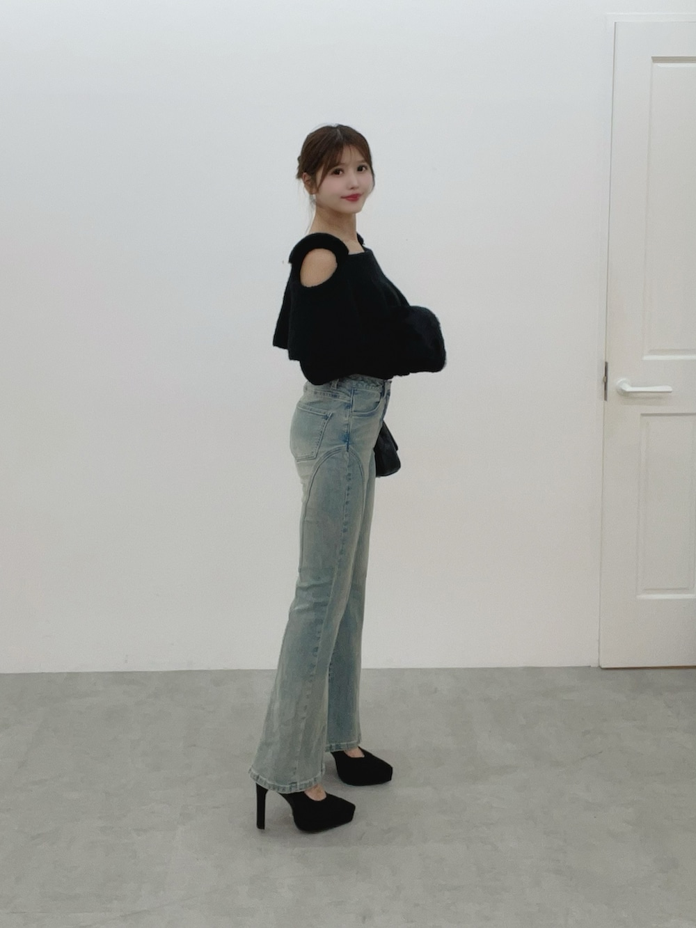 ブラック系のハンドバッグ、ブルー系のデニムパンツ、ブラック系のニット/セーターを着用したレディースの秋コーディネートの3枚目の写真