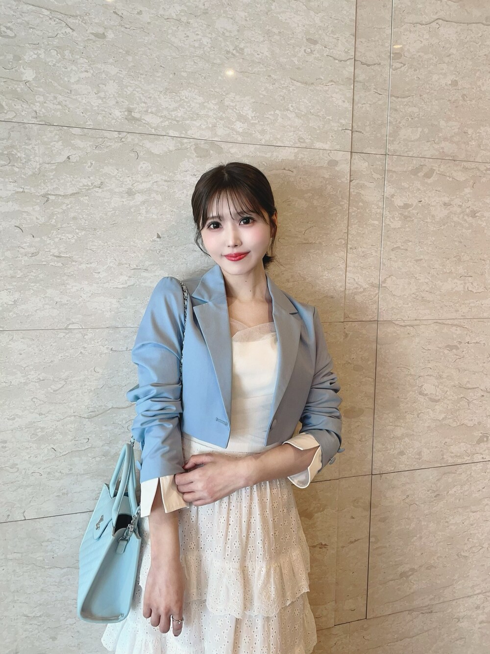 ホワイト系のスカート、ブルー系のハンドバッグ、ホワイト系のブーツを着用したレディースの春コーディネートの9枚目の写真