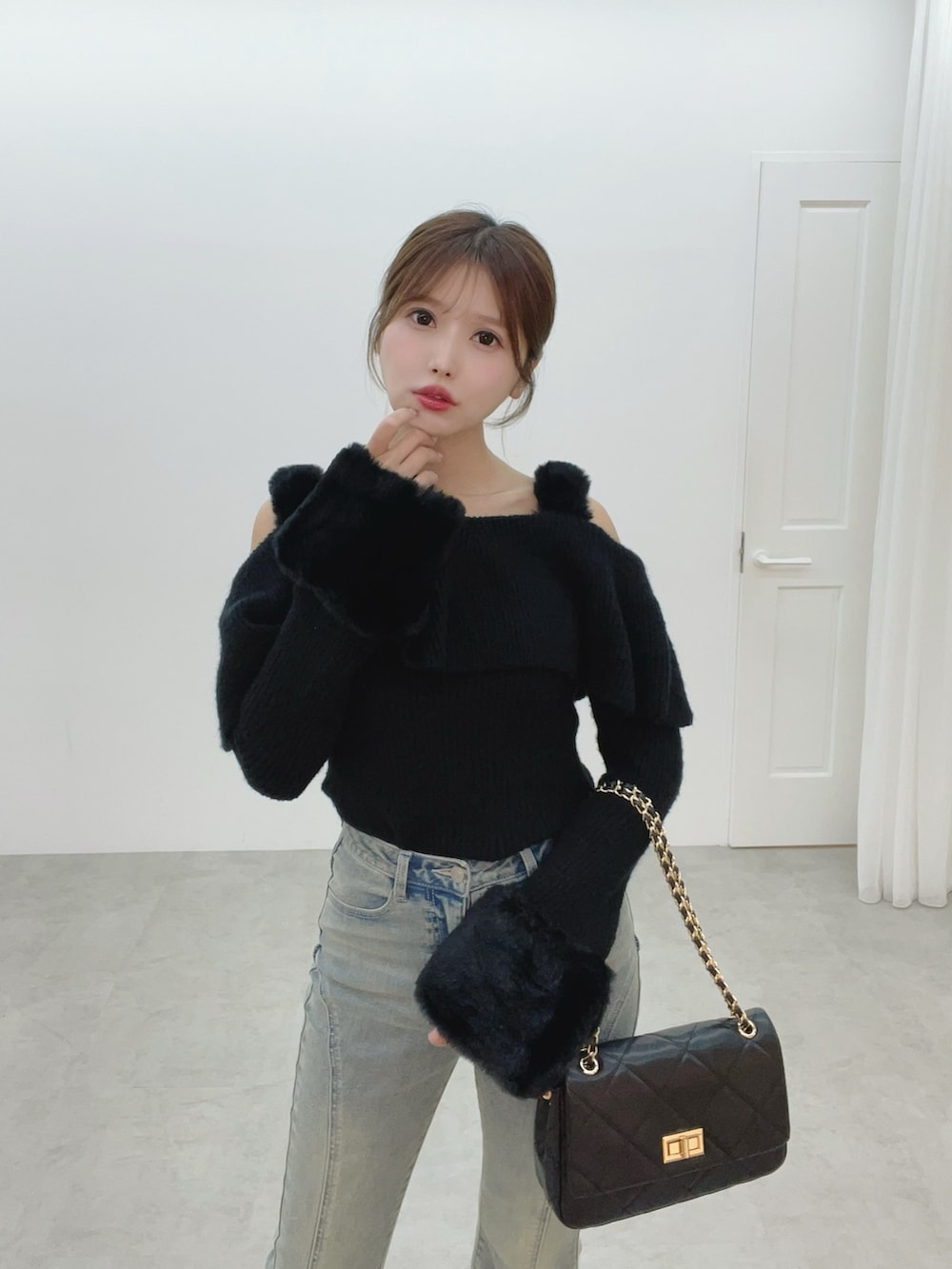 ブラック系のハンドバッグ、ブルー系のデニムパンツ、ブラック系のニット/セーターを着用したレディースの秋コーディネートの6枚目の写真