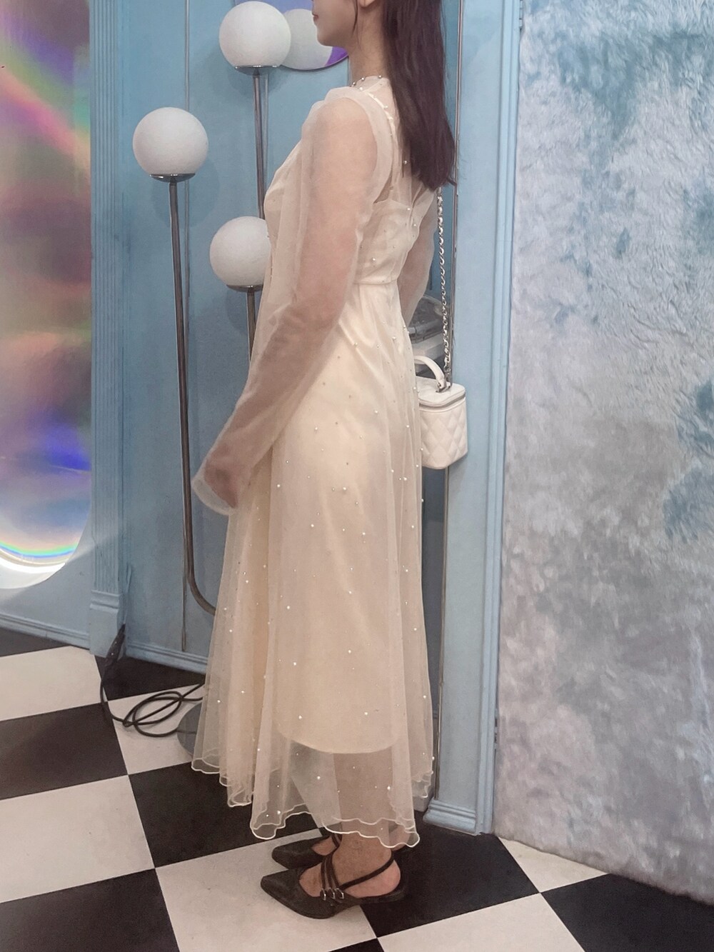 ホワイト系のワンピース、ブラック系のパンプス、ホワイト系のハンドバッグを着用したレディースの秋コーディネートの6枚目の写真