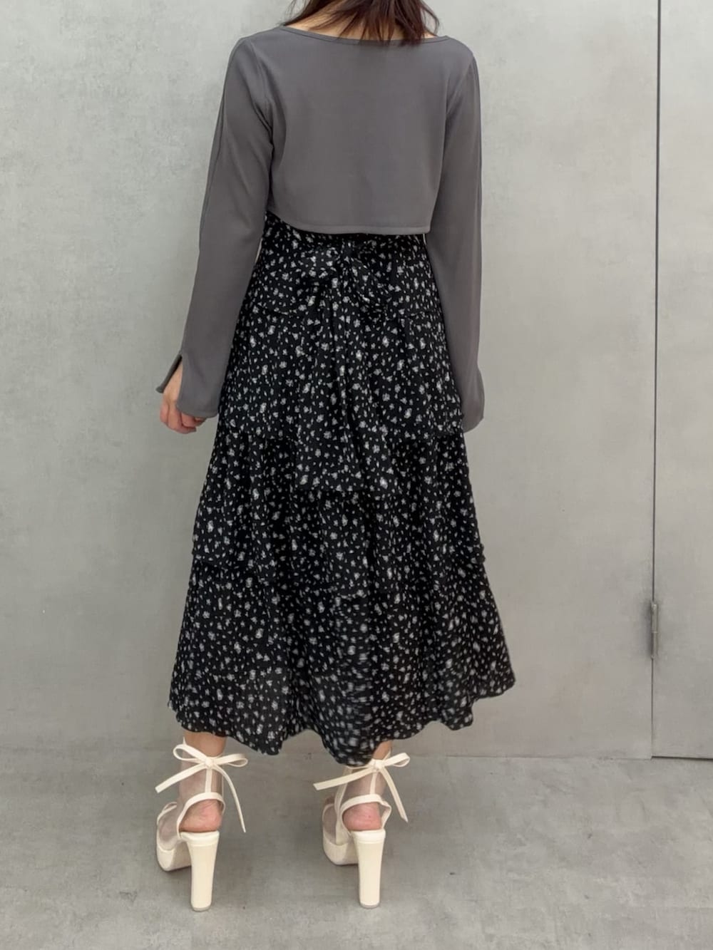 ブラック系のワンピース、ホワイト系のサンダル、グレー系のTシャツ/カットソーを着用したレディースの冬コーディネートの4枚目の写真