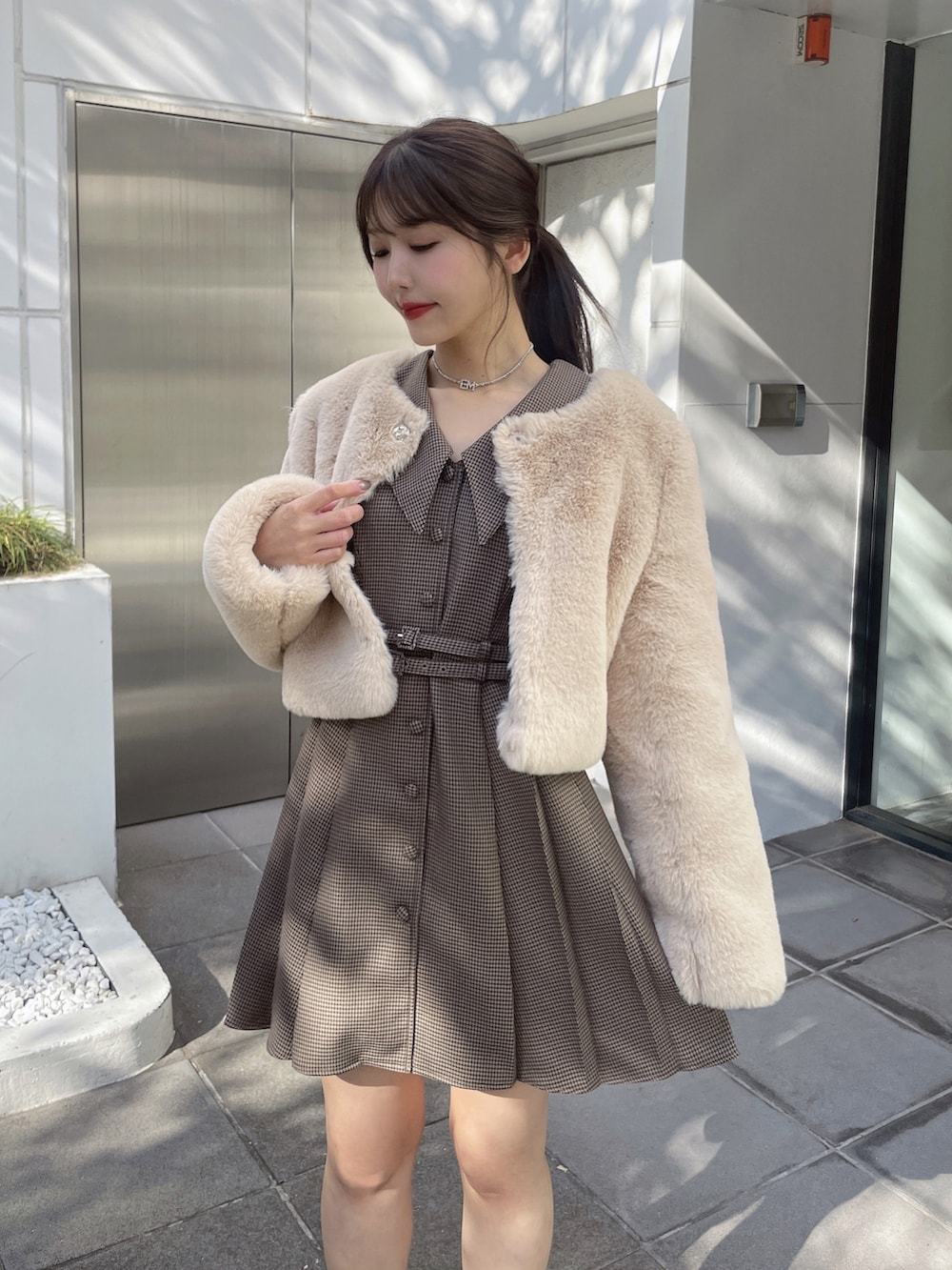 ブラウン系のワンピース、ベージュ系のその他アウター、ブラック系のローファーを着用したレディースの冬コーディネートの4枚目の写真