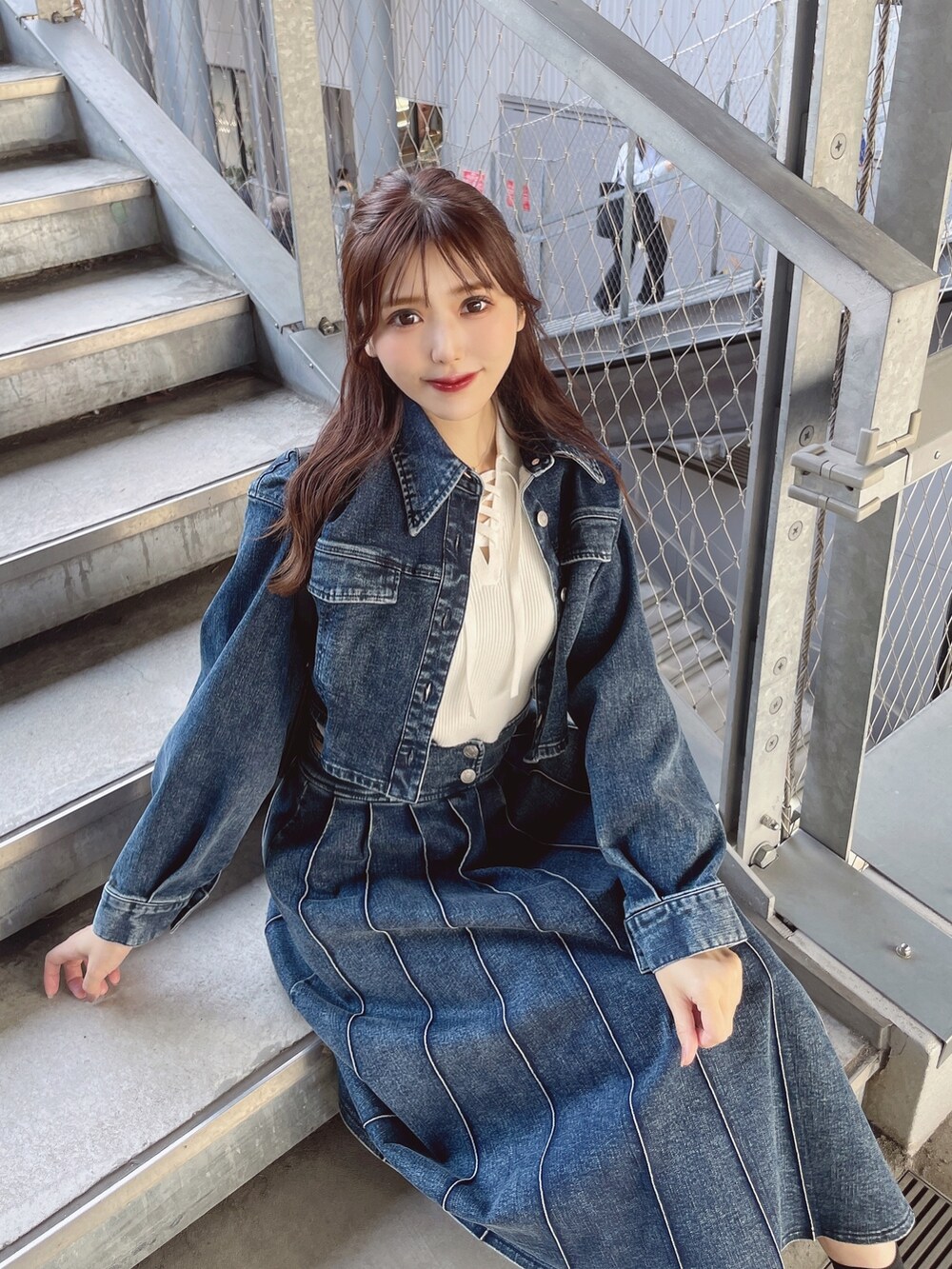 ブルー系のデニムスカート、ホワイト系のニット/セーター、ブルー系のデニムジャケットを着用したレディースの春コーディネートの2枚目の写真