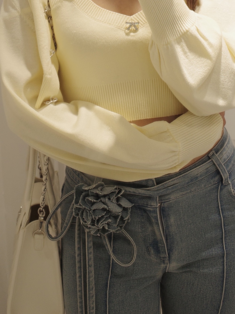 ブルー系のデニムパンツ、イエロー系のパンプス、イエロー系のニット/セーターを着用したレディースの夏コーディネートの2枚目の写真