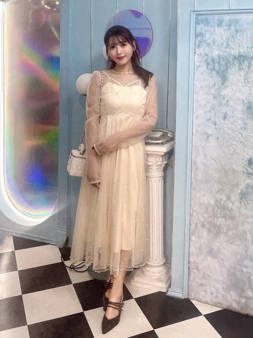 ホワイト系のワンピース、ブラック系のパンプス、ホワイト系のハンドバッグを着用したレディースの秋コーディネートの4枚目の写真