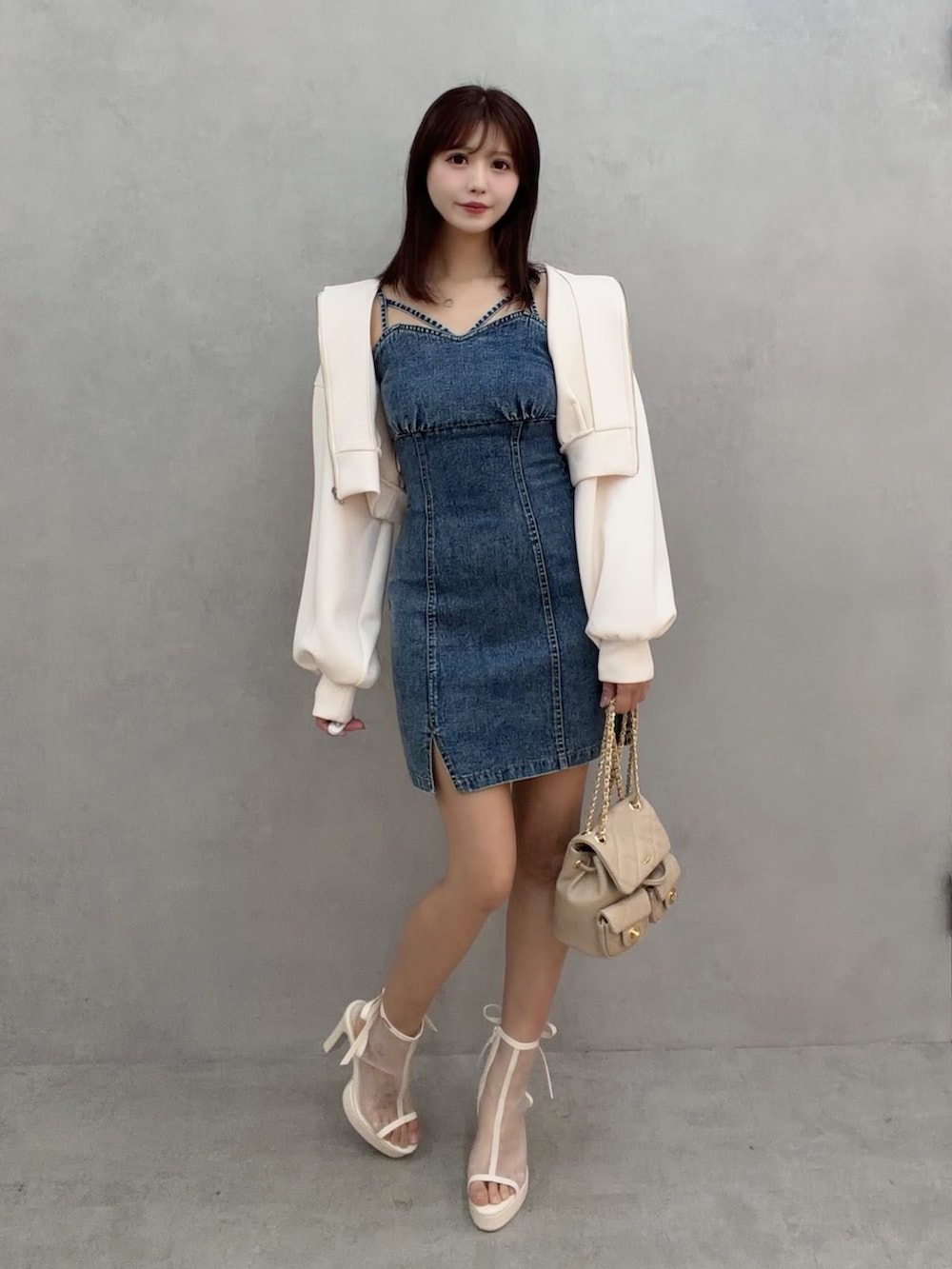 ブルー系のワンピース、ホワイト系のパーカー、ベージュ系のバックパック/リュックを着用したレディースの冬コーディネートの2枚目の写真